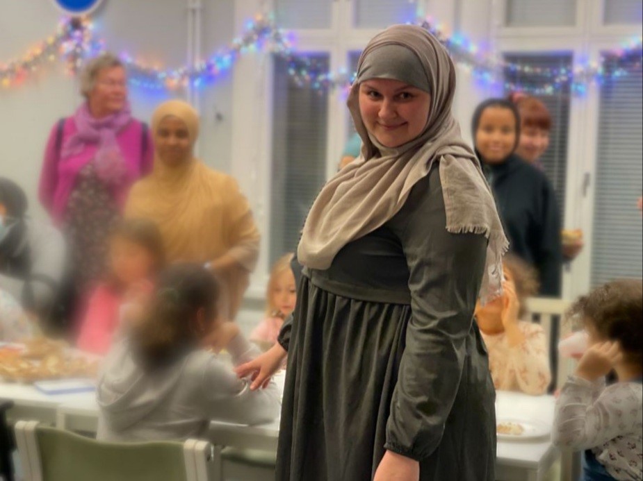 Nainen islamilaisittain puettuna, taustalla lapsia ja muista hunnutettuja naisia.