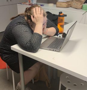 Opiskelija istuu tietokoneen ääressä nojaten käteensä.