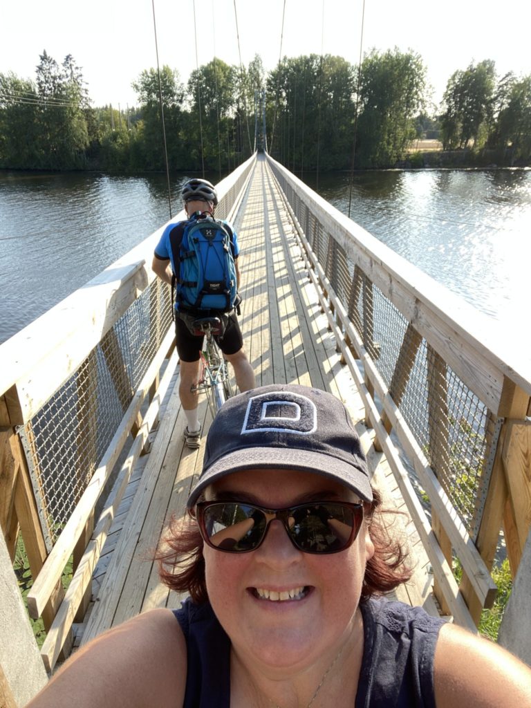 Helanan ottama selfie aurinkoisella sillalla. Taustalla mies polkemassa pyörää.