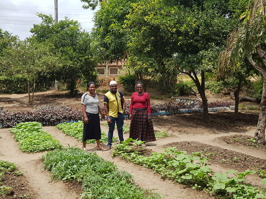 Kuvassa kolme iloista kasvimaan viljelijää Tansaniassa.