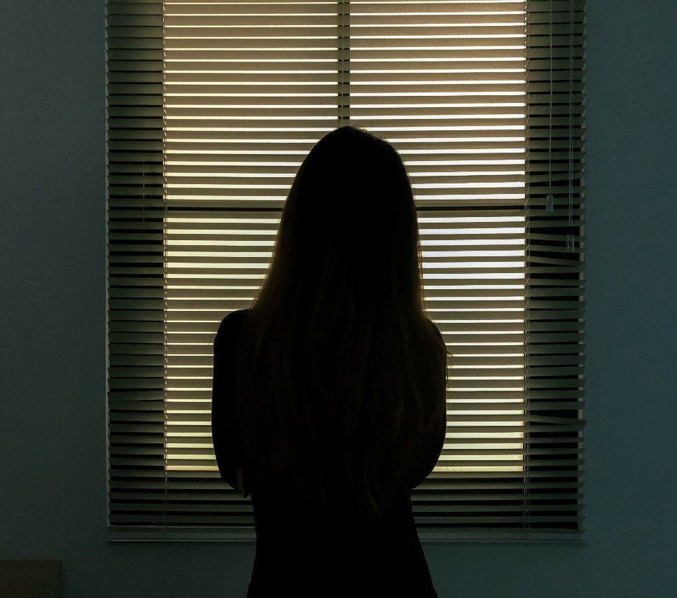 Naisen tumma hahmo ikkunan edessä, graafinen kuva.