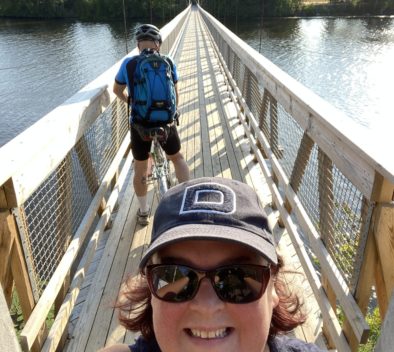 Helanan ottama selfie aurinkoisella sillalla. Taustalla mies polkemassa pyörää.